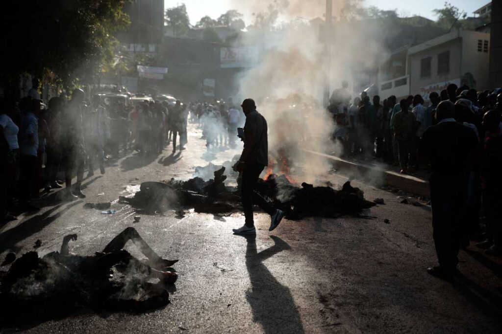 Transeúntes observan los cadáveres de presuntos miembros de una banda que fueron incendiados por una turba. Puerto Príncipe, 24 de abril de 2023. Odelyn Joseph / AP