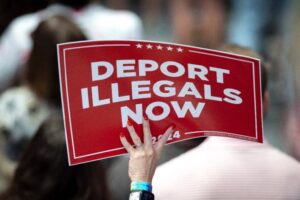 Un partidario de Donald Trump sostiene un cartel que dice "deporten a los ilegales ahora". Foto Afp