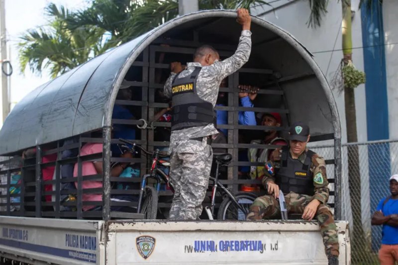 Guardias vigilan a haitianos detenidos en redadas de autoridades migratorias, durante su traslado al centro de recepción de migrantes en Haina (República Dominicana). EFE/Orlando Barría