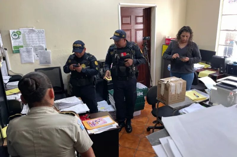 Agentes policiales revisan documentos en la oficina de la jefa de Permisos de la DGT, Mayra Herrera, quien ve su celular. Foto La Hora: José Orozco.