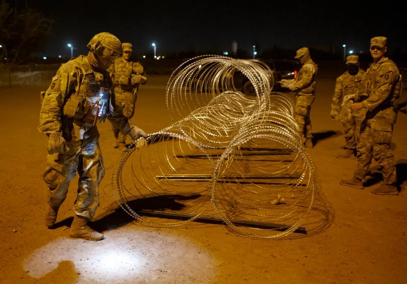 Elementos de la Guardia Nacional de Texas atan hileras de alambre de púas para su instalación cerca de una puerta en el muro fronterizo para evitar el paso de migrantes. Foto La Hora / AP.