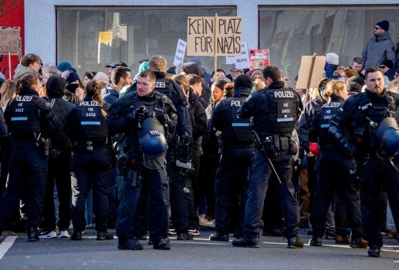 Agentes de policía se encuentran junto a manifestantes con un cartel que dice "no hay lugar para los nazis" durante una campaña electoral de AfD en Neu Isenburg, cerca de Frankfurt, Alemania, el 1 de febrero de 2025. Foto Ap