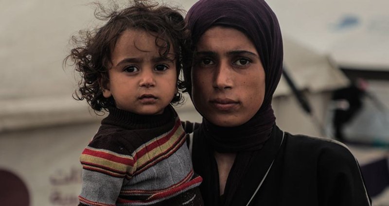 Una mujer palestina y su hijo frente a la tienda en la que viven en la ciudad de Gaza. Foto: © UNICEF/Mohammed Nateel